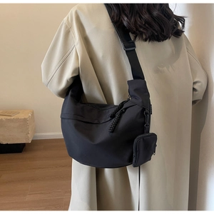 Detail view of large black nylon crescent bag with adjustable strap and small pouch