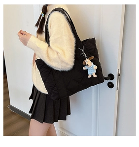 Detail of black quilted nylon tote bag featuring a cute plush dog pendant charm