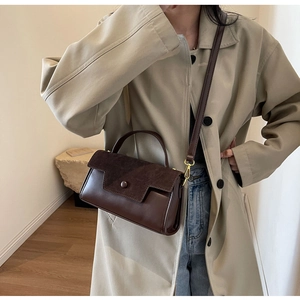 Detailed shot of dark brown vintage leather handbag with textured suede flap and gold buckle