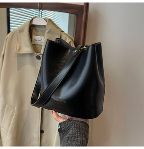 Detailed view of black bucket bag showing gold fashion bag text and smooth leather texture