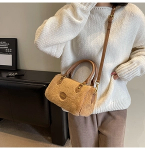Détail d'un sac oreiller en fausse fourrure marron clair avec poignées en cuir et logo