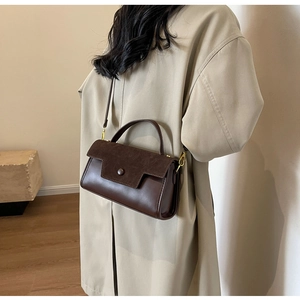 Detail of dark brown leather crossbody bag styled with a khaki trench coat