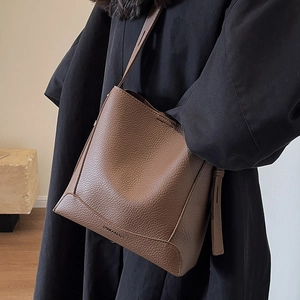 Brown lychee leather bucket bag with shoulder strap and embossed logo detail