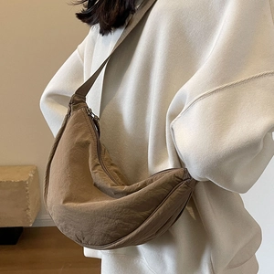 Minimalist brown half-moon canvas shoulder bag with adjustable strap on a model