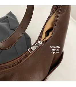 Dettaglio della cerniera argentata e della pelle marrone su borsa a secchiello retro