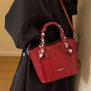 Elegant red structured leather handbag with heart silk scarf handle and gold text detail