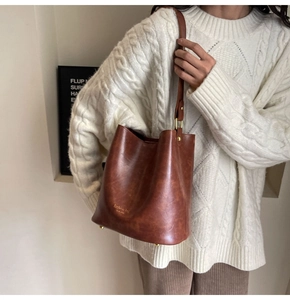 Detail of vintage brown leather bucket bag with gold lettering and metal bottom studs