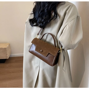 Detail view of dark brown leather crossbody bag styled with a beige classic trench coat
