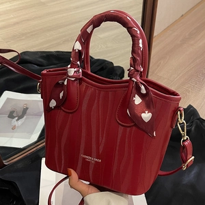 Elegant dark red wavy textured handbag with silk scarf handle and golden metal strap