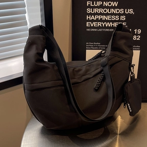 Black nylon crescent crossbody bag with small coin purse on a modern silver table