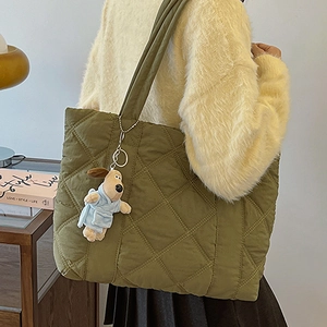 Quilted olive green nylon tote bag with puppy pendant shown in a stylish home setting