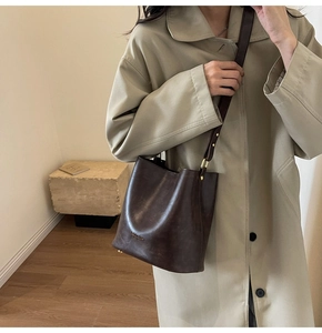 Detail view of vintage dark brown bucket bag featuring gold ring hardware and leather strap