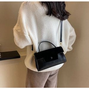 Detailed view of the black leather crossbody bag with gold hardware and flap closure