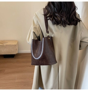 Detail view of the vintage dark brown bucket bag showing polished gold hardware and leather texture