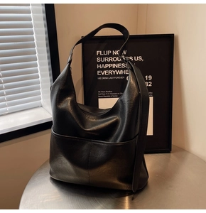 Dettaglio borsa hobo nera su tavolo in metallo con tasche frontali e tracolla larga