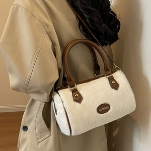 Sac Boston chic en fausse fourrure avec poignées en cuir et bandoulière porté avec un trench beige