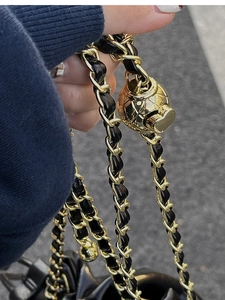 Detail of woven chain strap with gold metal ball adjuster and black leather weaving