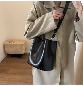 Detail of black faux leather bucket bag with gold rivets and fashion bag text