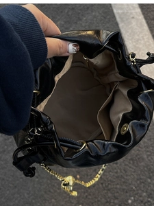Detail view of the black bucket bag interior showing beige lining and drawstring closure