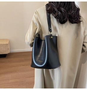 Detail of black leather bucket bag with gold studs and adjustable hardware