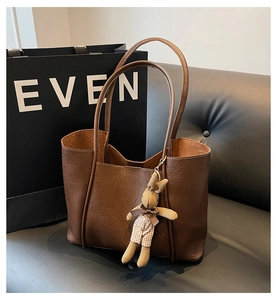 Detail of brown textured leather tote bag with a cute plush rabbit charm and large interior