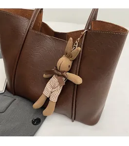 Detail of dark brown leather tote bag with vintage texture and handmade knit rabbit charm