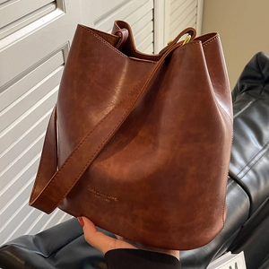 Retro caramel brown bucket bag in matte leather featuring wide shoulder strap and logo