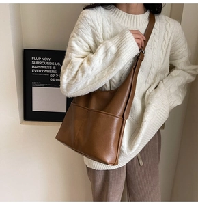 Dettaglio della borsa a secchiello in pelle marrone con due tasche frontali vintage