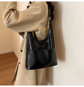Dettaglio di una borsa hobo nera in pelle PU premium abbinata a un cappotto beige classico