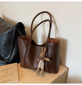 Detailed view of deep brown faux leather tote bag with a cute rabbit plush charm