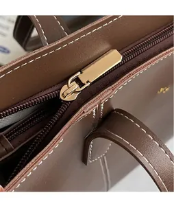 Detailed macro view of the dark brown leather tote with golden hardware zipper and stitching