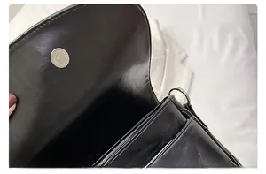 Detail of black leather bag showing multi-compartment interior and silver magnetic closure