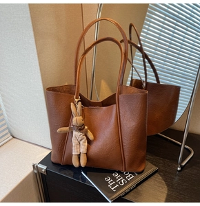 Brown tote bag detail with textured faux leather and a cute plaid bunny charm