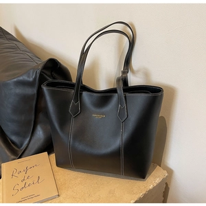 Detail of black leather tote bag with white contrast stitching and gold lettering
