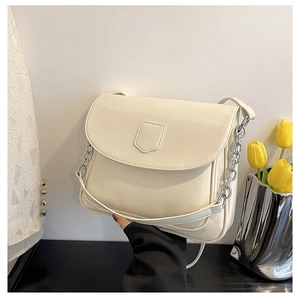 Detail of cream-white PU leather shoulder bag featuring shield emblem and silver chain link