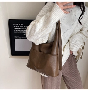 Dettaglio di una borsa a secchiello marrone in pelle PU con tasca esterna e tracolla larga