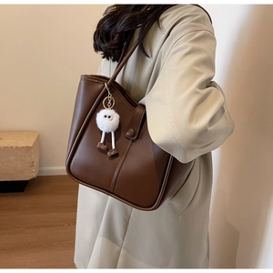 Borsa tote marrone scuro opaco con ciondolo di peluche portata a spalla casual