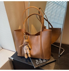 Close-up of brown faux leather tote bag with a cute woven bunny pendant on a counter