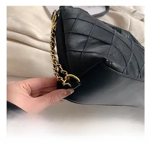 Détail de la chaîne en métal doré élégante sur le sac cabas noir matelassé en cuir