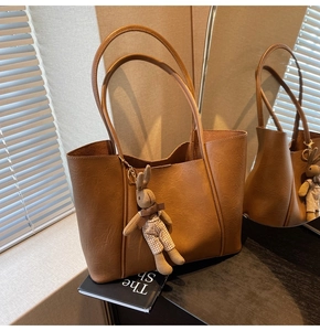 Close-up of brown faux leather tote bag with a cute rabbit plush charm and long straps