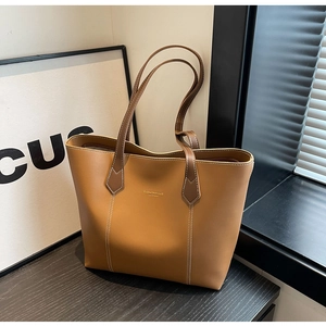 Close-up of brown leather tote bag featuring contrast stitching and gold lettering detail
