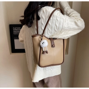 Dettaglio della borsa tote patchwork kaki e marrone con un ciondolo a mostro morbido