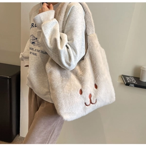 Dettaglio della borsa tote color crema con ricamo a forma di orso e texture in ecopelliccia