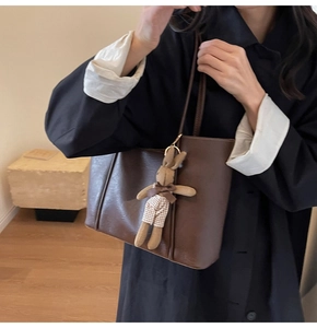 Brown faux leather tote bag detail with vertical stitching and a cute bunny pendant