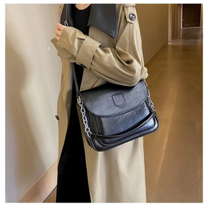 Detail of vintage black wrinkled leather shoulder bag with silver chain strap on model
