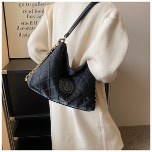 Détail du sac hobo matelassé noir avec chaîne dorée et logo M porté par le mannequin