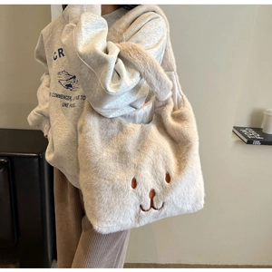 Dettaglio della borsa tote soffice bianco sporco con ricamo indossata dalla modella