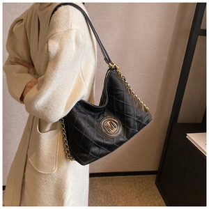Détail du sac hobo noir matelassé avec logo M doré et bandoulière sur le mannequin