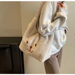Dettaglio della borsa tote beige in peluche con ricamo a forma di orso per l'autunno