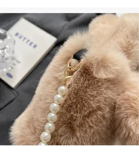 Detail of plush brown bag featuring premium gold hardware and elegant pearl chain strap